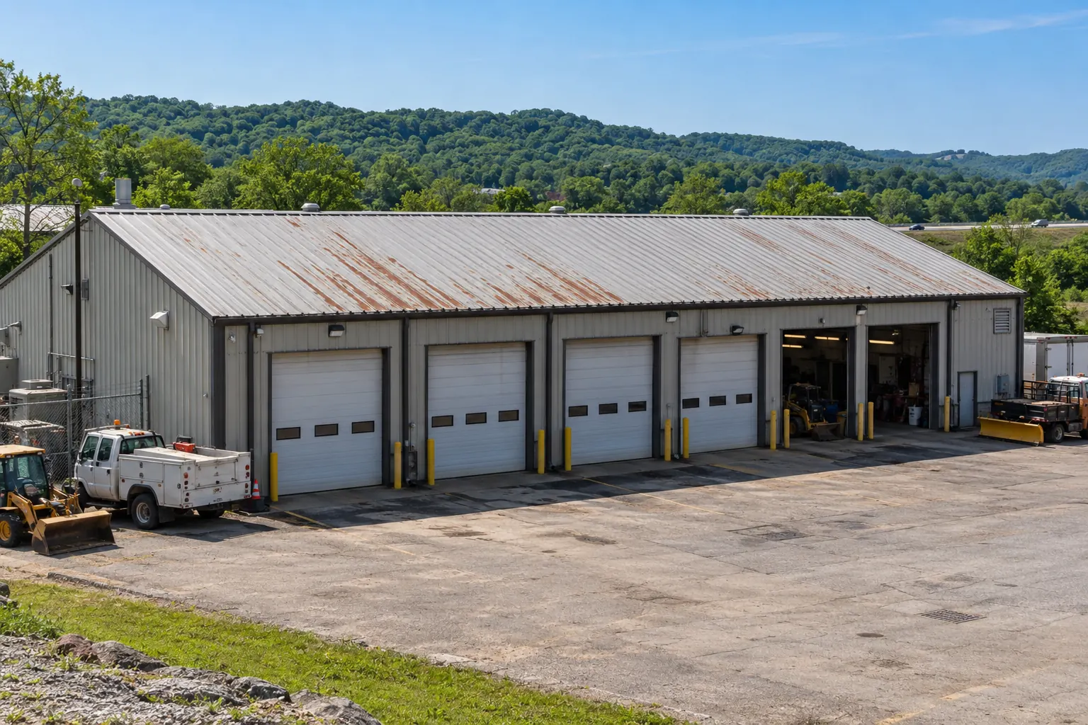 Metal shop building with four overhead doors and a weathered panel roof